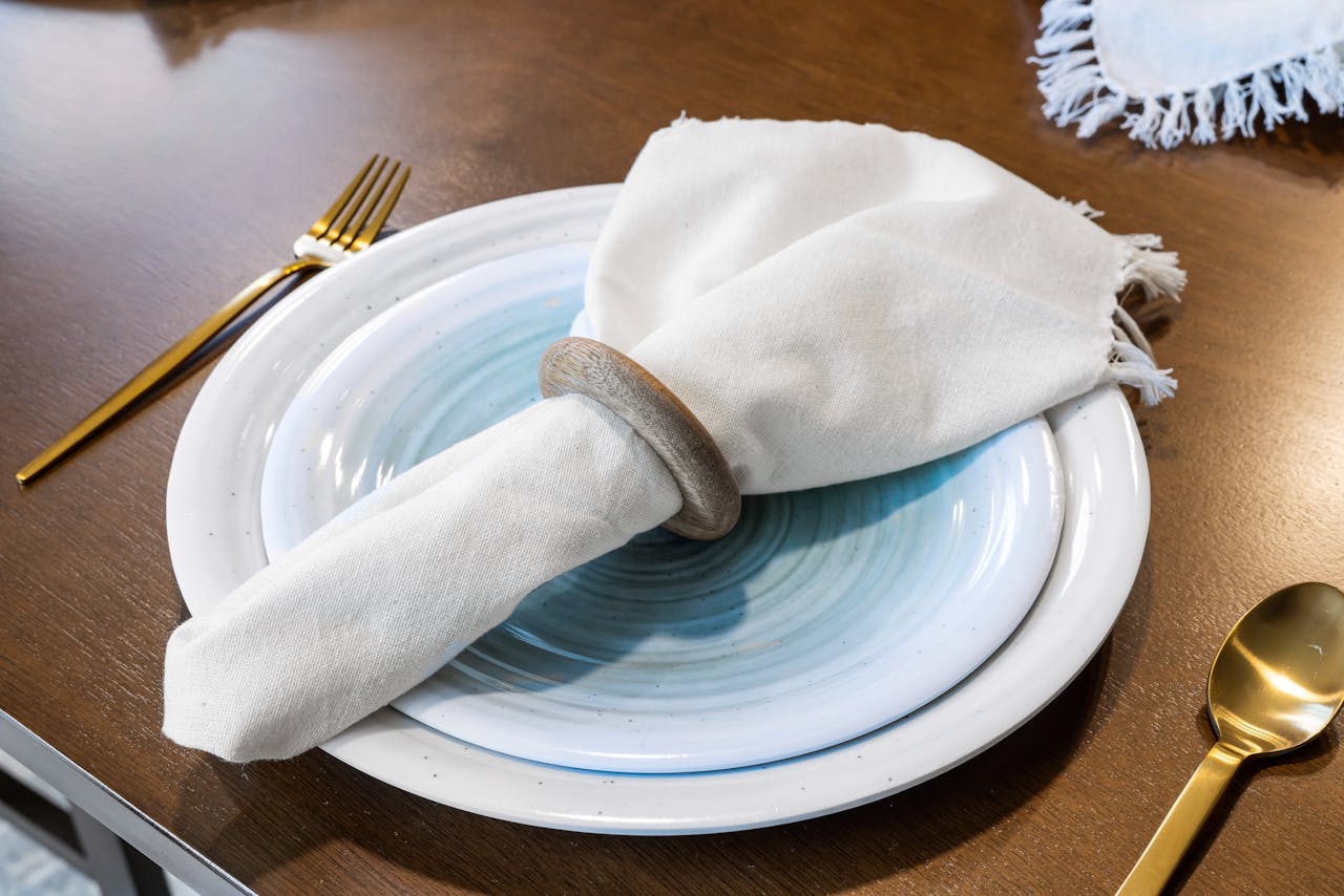 expertise-01 Stylish table setting featuring white ceramic plates, gold cutlery, and linen napkin for a sophisticated dining experience.